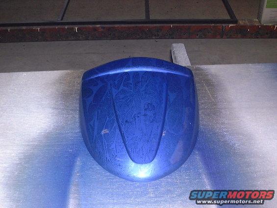 Blue painted car part with a swirling pattern, resting on a metallic surface